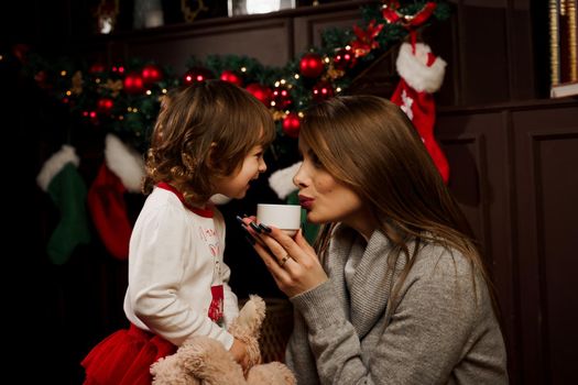 Mother and daughter preparing for christmas celebration. Having fun with family near new year tree. Pregnant woman with daughter