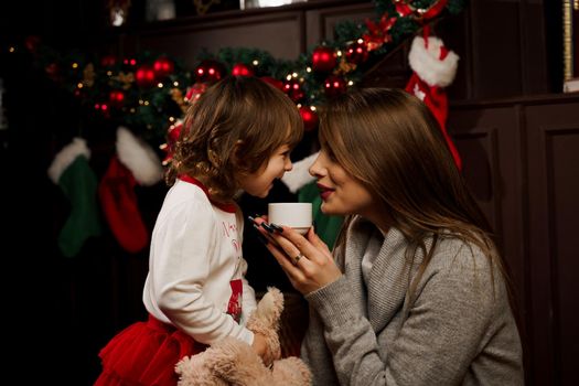 Mother and daughter preparing for christmas celebration. Having fun with family near new year tree. Pregnant woman with daughter