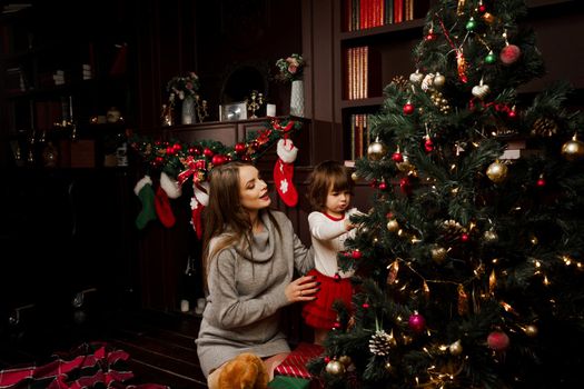 Mom and daughter decorate the christmas tree before the new year. Family traditions. Preparing for new year celebration