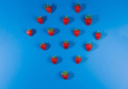 Red strawberries on blue background. Ripe tasty berry