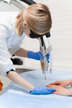 Laser treatment of onychomycosis. fungal infection on the hands of a young girl in medical clinic.