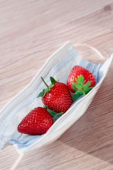 Strawberry on medical mask for protection against coronavirus covid-19.