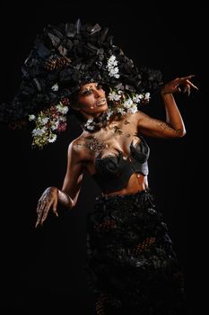 Portrait of a model in a headdress and dress made of coal. Bright makeup and body art.