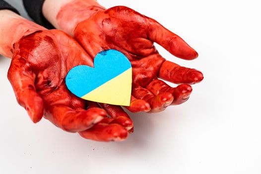 Woman with hands covered in blood holding a heart with the flag of ukraine on a white background