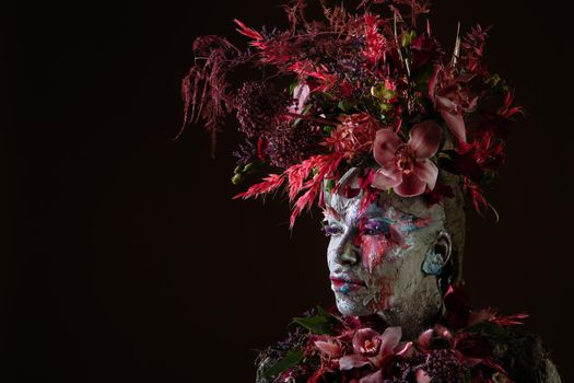 A girl smeared with clay. The model has a headdress made of flowers.