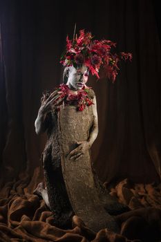 A girl smeared with clay. The model has a headdress made of flowers.