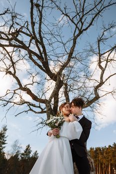 The bride and groom are standing in a snow-covered forest