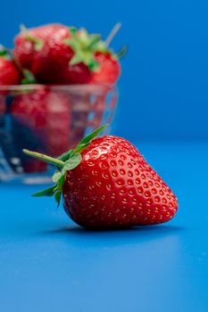 Bunch of strawberry in bowl on blue background. Yummy summer fruit