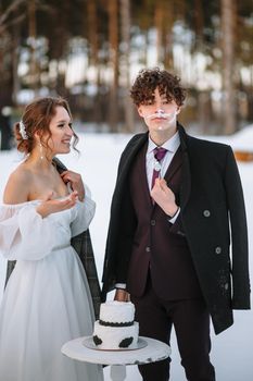 The bride and groom, smeared with wedding cake. Shooting in the winter forest.