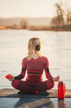 A girl does yoga in winter on the ice of the lake