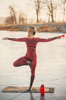 A girl does yoga in winter on the ice of the lake