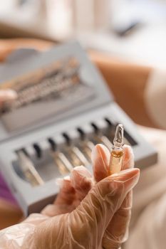 Ampoule with vitamins in the hands of a beautician