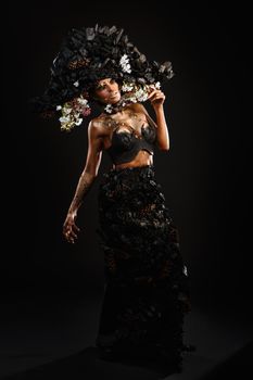 Portrait of a model in a headdress and dress made of coal. Bright makeup and body art.