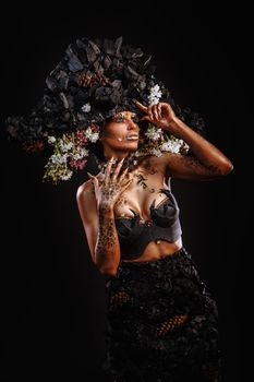 Portrait of a model in a headdress and dress made of coal. Bright makeup and body art.