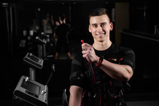 Man with electronic contactor of EMS suit in gym. Sport training in electrical muscle stimulation suit