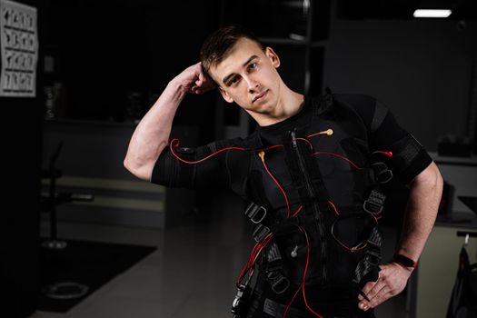 Making physical exercises using EMS suit in gym. Sport training in electrical muscle stimulation suit.