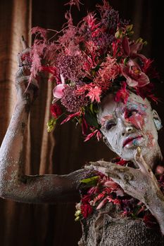 A girl smeared with clay. The model has a headdress made of flowers.