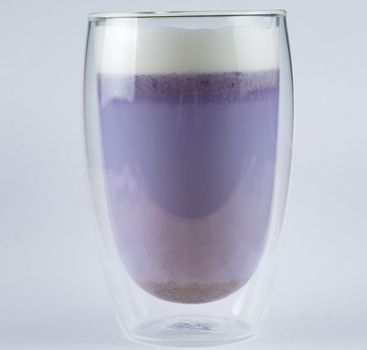 Purple goji matcha on blue background. Matcha cocktail in double glass cup