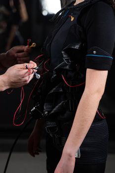 Wires from EMS suit in gym. Sport training in electrical muscle stimulation suit. Making physical exercises.