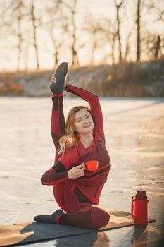 A girl does yoga in winter on the ice of the lake