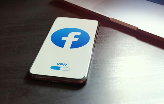 MOSCOW, RUSSIA - MAY 03, 2022: iphone lying on a wooden table, on the screen Facebook social application logo, which starts only after turning on the vpn connection. Government censorship concept.
