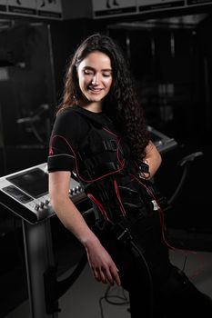 Girl in EMS suit in gym. Sport training in electrical muscle stimulation suit