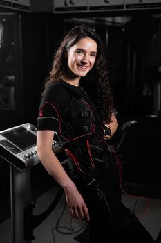 Girl in EMS suit in gym. Sport training in electrical muscle stimulation suit