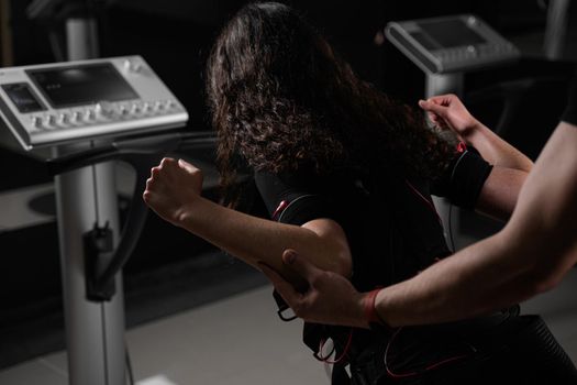 Making physical exercises using EMS suit in gym. Sport training in electrical muscle stimulation suit