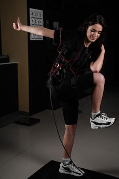 Making physical exercises using EMS suit in gym. Sport training in electrical muscle stimulation suit