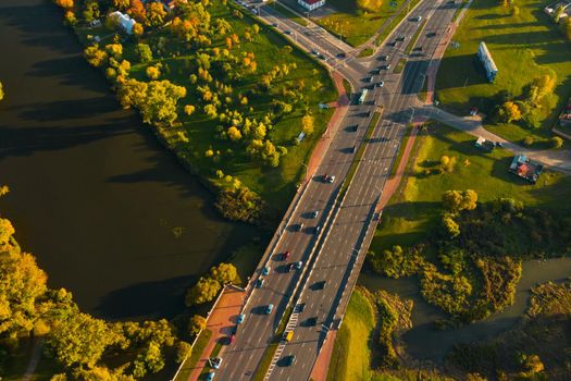 View from the height of the road with cars near the autumn Park.