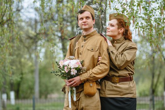 Portrait of two military lovers at a flowering tree. Warm spring, people are returning from the war