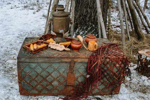 An old samovar standing on a chest in the winter forest.