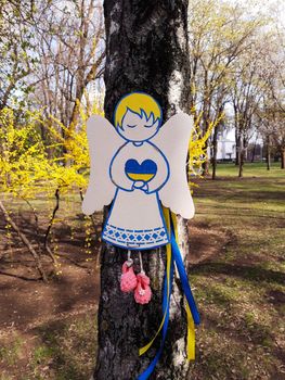 Cardboard angels on a birch trunk in a park in memory of the Ukrainian children who died in the war with Russia.