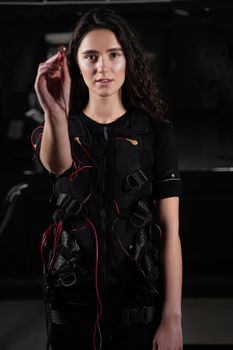 Girl with electronic contactor of EMS suit in gym. Sport training in electrical muscle stimulation suit