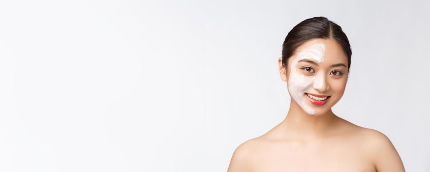 Charming pleasant woman applying cream on half face.