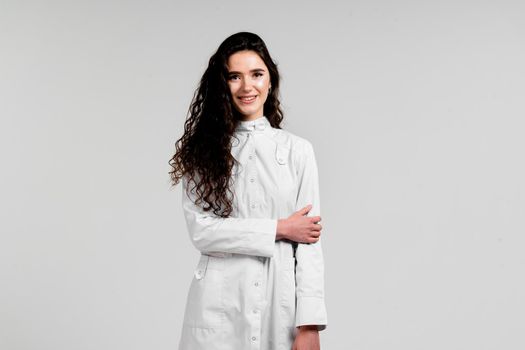 Girl surgeon in medical dress with curly hair on white background. 3rd wave of coronavirus covid-19 epidemy.