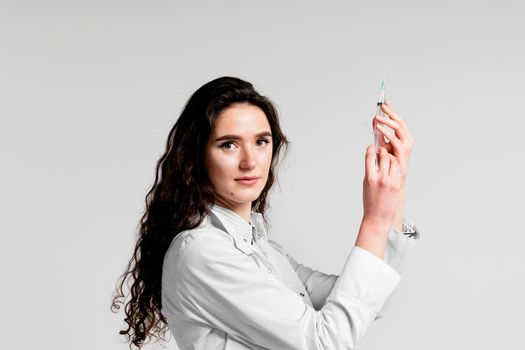 Doctor holding syringe with coronavirus vaccine. Covid-19 Vaccination. Stop quarantine. Attractive girl in medical gloves with syringe and medication