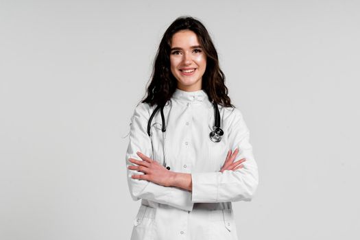 Girl surgeon in medical dress with curly hair on white background. 3rd wave of coronavirus covid-19 epidemy.