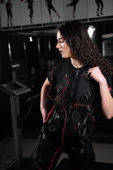 Girl in EMS suit in gym. Sport training in electrical muscle stimulation suit