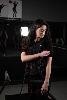 Girl in EMS suit in gym. Sport training in electrical muscle stimulation suit