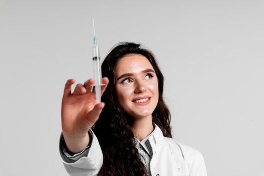 Doctor holding syringe with coronavirus vaccine. Covid-19 Vaccination. Stop quarantine. Attractive girl in medical gloves with syringe and medication