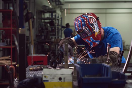 Professional Heavy Industry Welder Working Inside the factory, Wears Helmet and Starts Welding. Selective Focus. High-quality photo