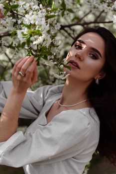 Lovely girl near blooming trees in the park. Outdoor walking in at sunny day. Lifestyle of young woman