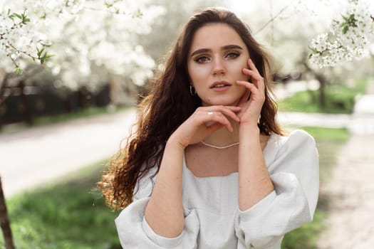 Lovely girl near blooming trees in the park. Outdoor walking in at sunny day. Lifestyle of young woman.