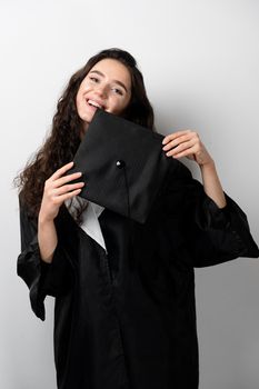 Distance learning online. Study at home. Graduation from college. Graduate in black robe smile on white background. Funny woman smiling after successful finish university and complete master degree