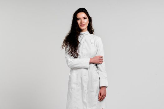 Girl surgeon in medical dress with curly hair on white background. 3rd wave of coronavirus covid-19 epidemy.