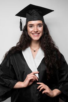 Graduate girl with master degree in black graduation gown and cap on white background. Happy young woman careerist have success in her business.