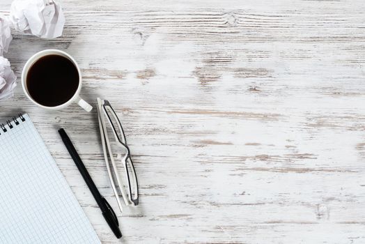 Still life of manager workplace in office with crumpled paper balls. Flat lay wooden desk with blank notebook and cup of coffee. Creativity and idea generation. Brainstorming meeting in design studio.