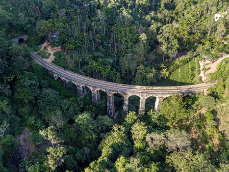 Sri Lanka. The attraction is the ancient railway Nine-arch Demodara Bridge in the midst of a dense tropical forest. Shooting from the air on a drone. Sunny day, sunset.