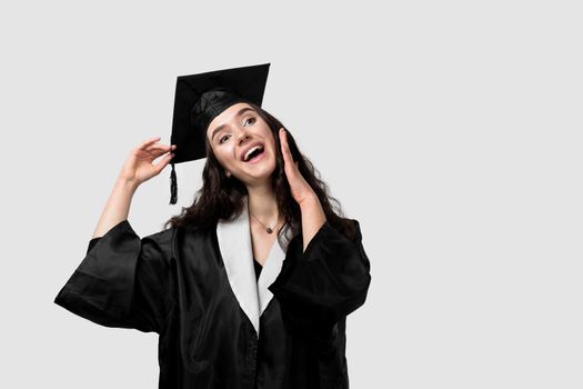 Surprised bachelor girl in graduation robe and cap on white background. Happy and funny young woman smile. Student achieve master degree in univesity